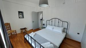 a bedroom with a bed with white sheets and a chair at Kampi Apartment in Chora Folegandros