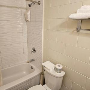 uma casa de banho branca com um WC, uma banheira e um lavatório. em Pacific Rim Motel em Ucluelet