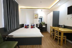 a bedroom with a bed and a table and a desk at Ruby Star Hotel Nam Quoc Cang in Ho Chi Minh City