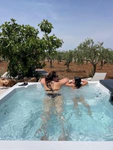 卡斯特拉納格羅泰的住宿－Il TrullOzio，两个妇女在游泳池的按摩浴缸里