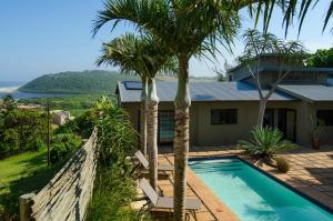 een huis met een zwembad en palmbomen bij Villa La Mercy Chalet No load shedding or water outages in La Mercy