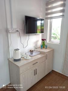 a tv on a wall in a room with a cabinet at Teratak Yoi in Pantai Cenang