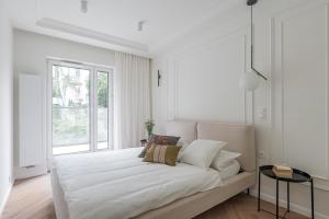 a white bedroom with a bed and a window at Apartament PREMIUM in Poznań