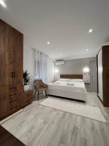 a white bedroom with a bed and a chair at Apartments Hillside in Ulcinj +95 photos