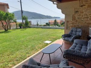 a patio with couches and a table and a lawn at Casa con vistas al mar in Noya