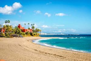 a sandy beach with palm trees and the ocean at Blue Ocean Apartments in Benalmádena
