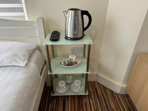 a nightstand with a tea kettle on it next to a bed at Namaste Palace Hotel in Norwich