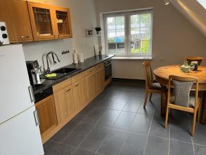 a kitchen with a table and a sink and a refrigerator at Toms great house of hygge in Süderstapel