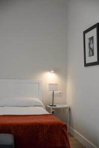 een slaapkamer met een bed met een rode deken en een lamp bij Hostal Jakiton in Palmanova