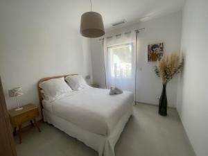 a white bedroom with a bed and a window at La maison des Lilas in Aix-en-Provence
