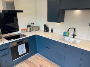 考斯Stylish 1 Bedroom Flat in Heart of Cowes的带蓝色橱柜和水槽的厨房
