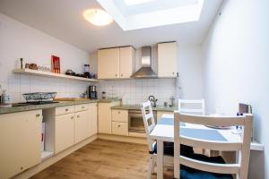 eine Küche mit weißen Schränken und einem Tisch und Stühlen in der Unterkunft Bosrust Bungalow in Vught