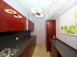 a kitchen with red cabinets and a counter with a sink at Dünenresidenz Regina Elena Ferienwohnung am Strand in Calambrone