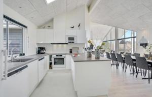 a kitchen with white cabinets and a table with chairs at Lovely Home In Væggerløse With Sauna in Marielyst