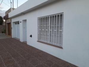 a white building with a window and a door at Alojamiento BRAGADO in Bragado