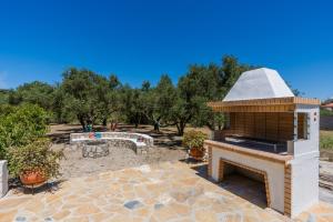 a backyard with a fireplace and a bench and trees at West Point House in Agía Thékli