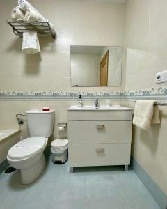 ein Badezimmer mit Toilette, Waschbecken und Spiegel in der Unterkunft Chalet Portosin con piscina al lado de la playa in Goyanes + 22 Fotos