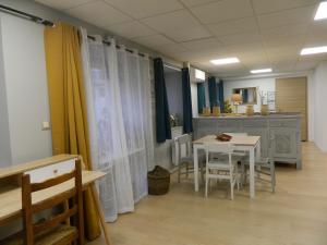 a room with a table and chairs and a kitchen at La Lusitanie,meublé de tourisme in Morteau