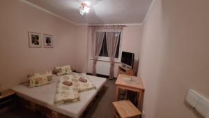 a small bedroom with a bed and a television at Vila Tatranka in Stará Lesná