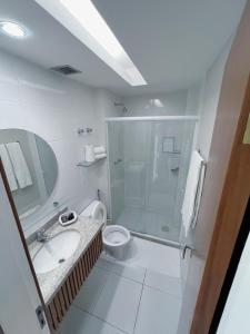 a bathroom with a shower and a toilet and a sink at Violeta Meaípe Hotel in Guarapari