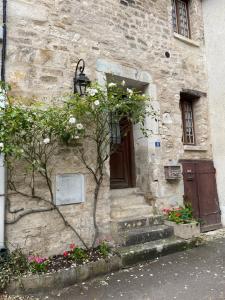 a stone building with a door and some flowers at La Maison d'Alienor, Gite à Chablis in Chablis