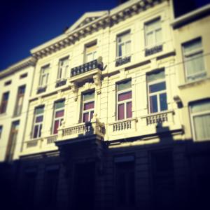 Edificio alto de color blanco con ventanas y balcones en Boomerang Antwerp, en Amberes