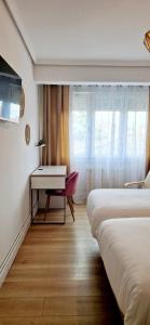 a hotel room with two beds and a desk at Apartamento I Cruces Metro BEC in Barakaldo
