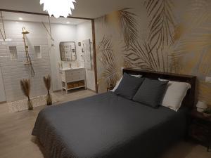a bedroom with a large bed and a bathroom at L'atelier Détente et Spa in Caudrot
