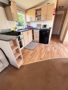 uma cozinha com armários de madeira e um frigorífico preto em Van number 123 Beautiful Caravan sleeps 4 to 6 em Aberystwyth