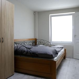 a bedroom with a bed with a wooden frame and a window at Róza Vendégházak- Tényő in Tényő
