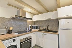 a kitchen with white cabinets and a sink at Le Plaisant - Nîmes plein centre in Nîmes +18 photos