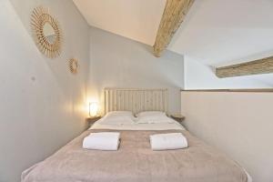 a bedroom with a large bed with two white towels at Le Plaisant - Nîmes plein centre in Nîmes