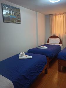 due letti in una stanza con lenzuola blu di Hotel TIKA AYNA Cerca a la plaza de Armas CUSCO a Cuzco