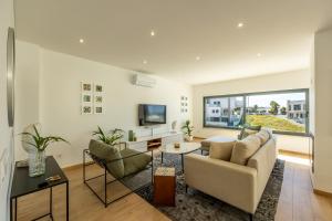 a living room with a couch and chairs and a tv at Silver Coast Beach Villa-Casa de Luxo com Piscina e Vista Mar in Lourinhã