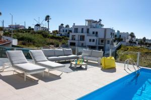 a group of chairs and a table next to a pool at Silver Coast Beach Villa-Casa de Luxo com Piscina e Vista Mar in Lourinhã