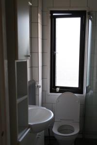 a bathroom with a toilet and a sink and a window at Lägenhet nära hav och centrum in Halmstad