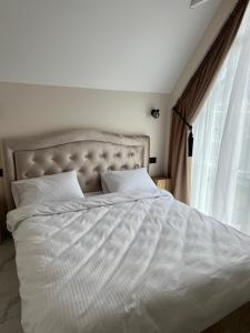 a bed with white sheets and pillows next to a window at Amber Sand apartamentai in Palanga