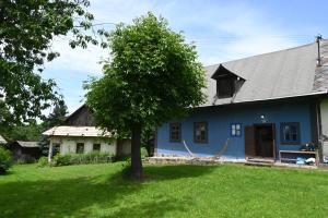 a blue house with a tree in the yard at Modrá chalupa in Pliešovce