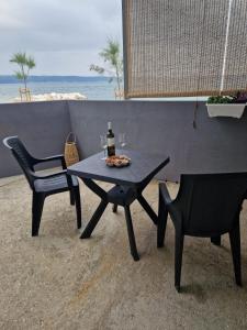 a table with a bottle of wine and two chairs on the beach at Apartman Sandra in Podstrana