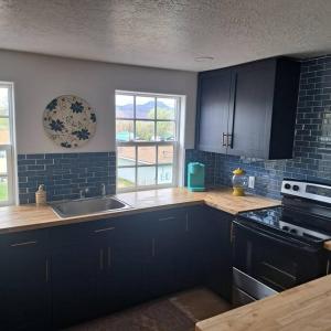 a kitchen with dark blue cabinets and a sink at Marysvale House by Bryce and Piute Trail in Marysvale