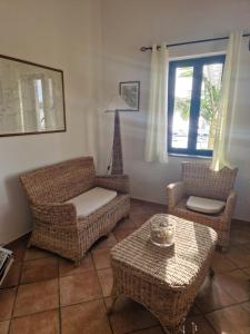 a living room with wicker furniture and a window at SANTA MONICA Residence Hotel in Ricadi
