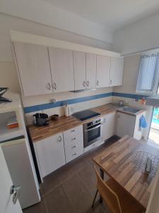 une cuisine avec des armoires blanches et une table en bois dans l'établissement AIDIPSOs PARK 2, à Loutra Edipsou