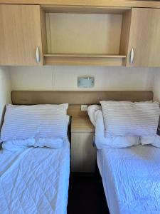 two beds sitting next to each other in a bedroom at Van number 123 Beautiful Caravan sleeps 4 in Aberystwyth