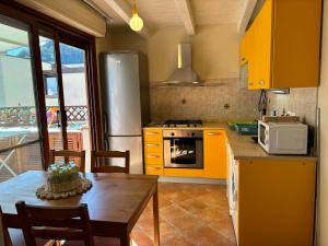 eine Küche mit gelben Schränken und einem Tisch mit einer Mikrowelle in der Unterkunft Casa vacanze La Chicca in Capo dʼOrlando