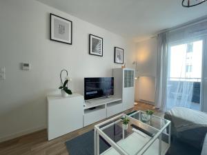 a white living room with a tv on a white cabinet at Apartment near to Paris CDG in Aulnay-sous-Bois