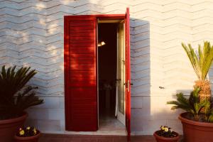 an open red door on a white building with plants at Villa Rosanna's Haven Terrazza e Parcheggio- by Gessica Home in Antonelli
