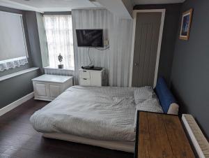 a bedroom with a bed and a tv on the wall at Free Parking, 1 bed flat Park street in Weymouth
