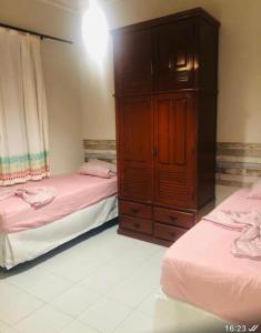a bedroom with two beds and a wooden cabinet at Casas Aracaju Temporada inteira 900 m da passarela in Aracaju