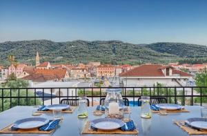 a table with plates and glasses on a balcony at Hvar luxury Villa and pool with view in heart of Stari Grad in Stari Grad