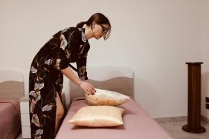eine Frau legt ein Kissen auf ein Bett in der Unterkunft Villa Rosanna's Haven-Relax a pochi minuti da Monopoli in Antonelli